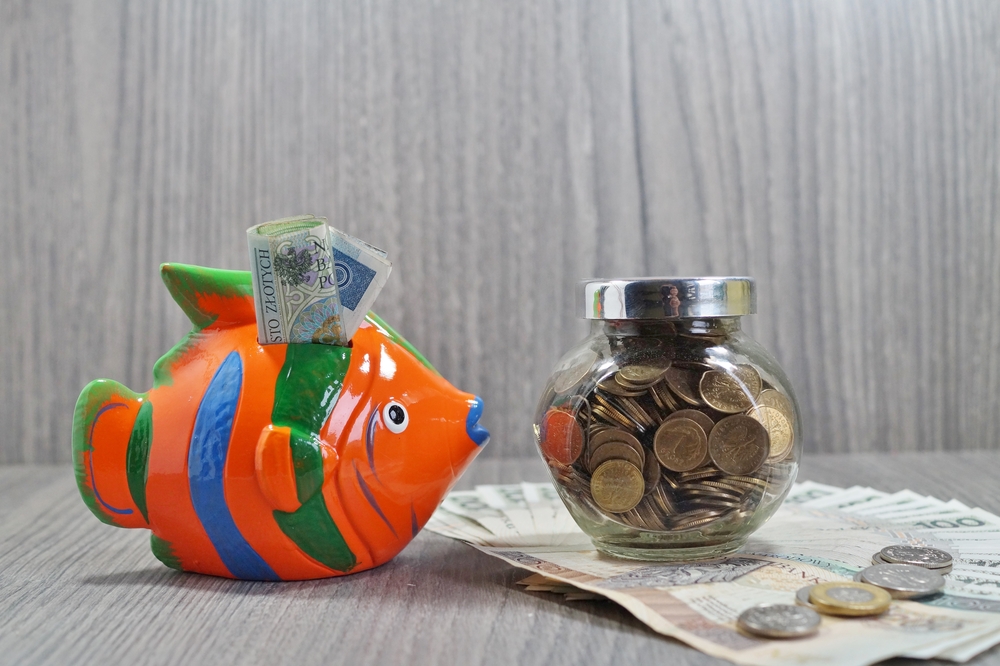 Fish money box filled with foreign currency notes and a glass jar filled with foreign currency coins