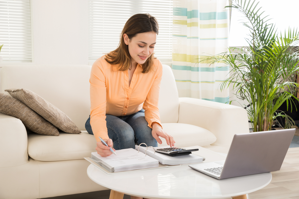 Woman working out her finances on a calculator and making notes