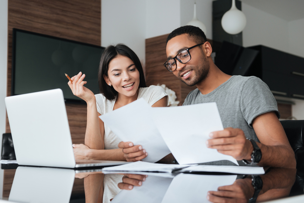 A man and women looking over their finances on a laptop and letters at a desk