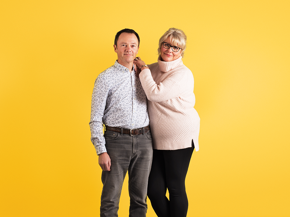 over50s-couple-yellow-1000x750 Couple in their 50s embracing against a yellow background