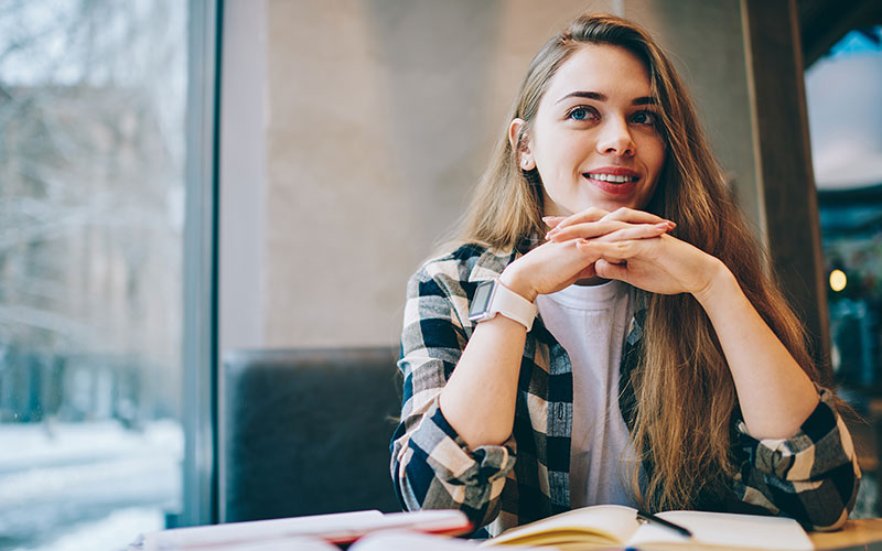 great-expectations-800x500 A smiling woman, sitting at a table, with an open journal in front of her.