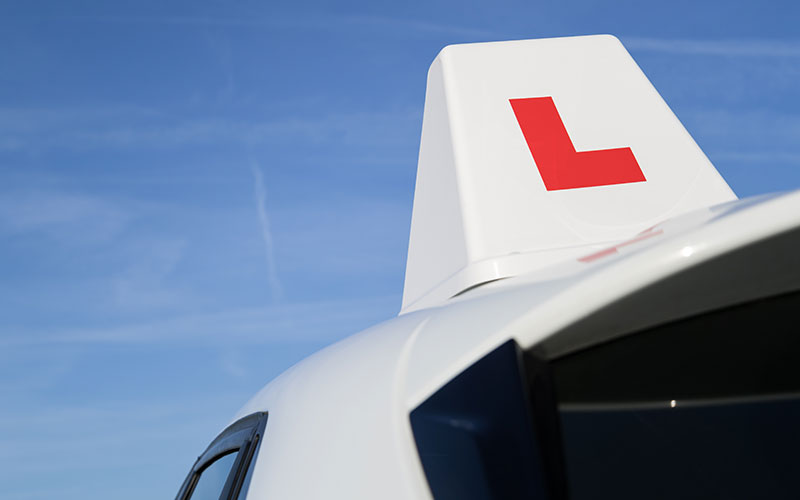 A white car with a learner box sign on the roof.