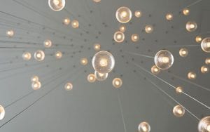 Dozens of lightbulbs hung from a ceiling, of varying lengths.