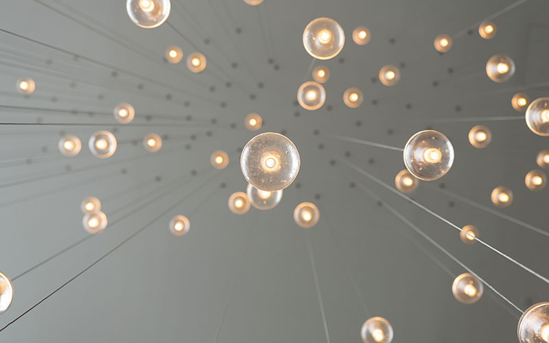 simple-ways-make-your-life-greener-800x300 Dozens of lightbulbs hung from a ceiling, of varying lengths.