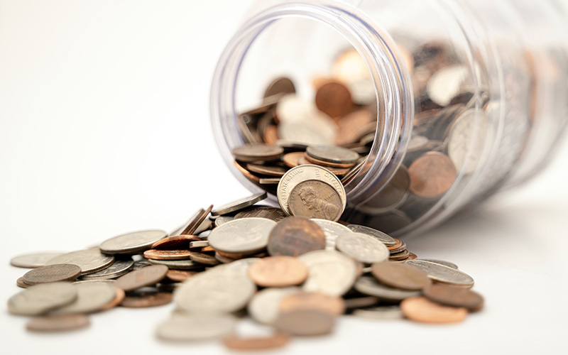 trick-yourself-into-saving-800x500 A jar full of pennies, tipped over with some spilling out.