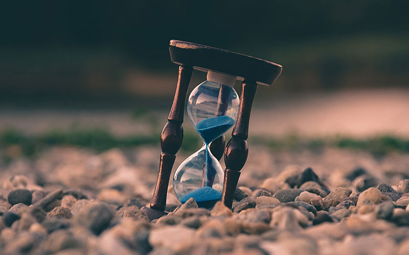 An hourglass sitting on pebbles.
