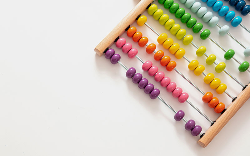 A wooden abacus with multicoloured beads, sitting on a white background.