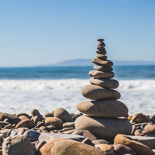 encouraging-balanced-attitude-towards-money-500x500 A stack of balancing pebbles on a beach