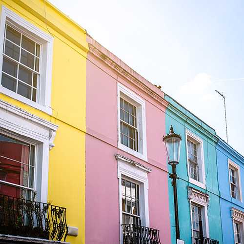 equity-release-explained-500x500 A row of bright multi-coloured houses with a blue sky behind them.