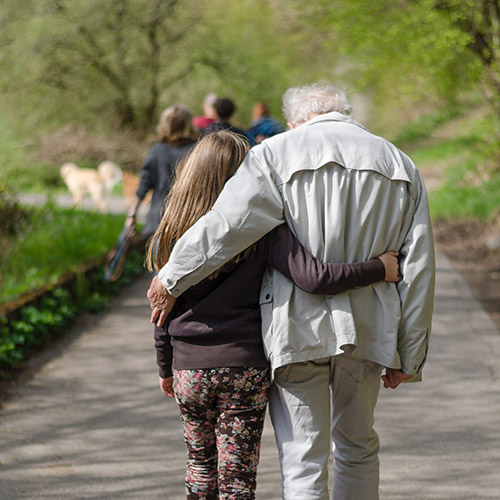 An elderly father walking down a path with his daughter