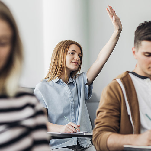 fund-performance-3-500x500 A teenage girl in a classroom with her hand up, waiting to ask a question