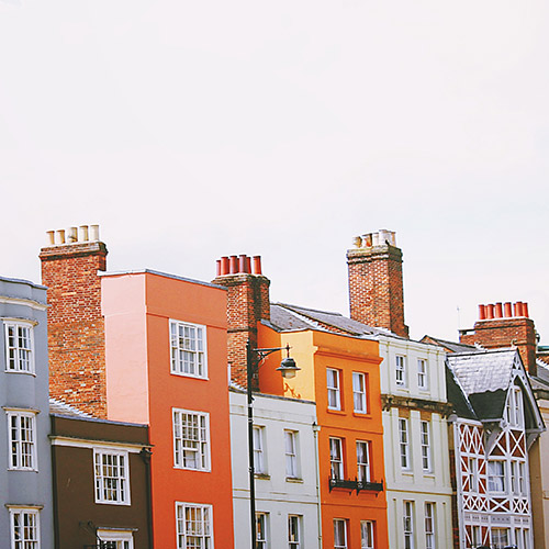how-much-does-it-cost-500x500 A row of houses, with a white cloudy sky behind them.