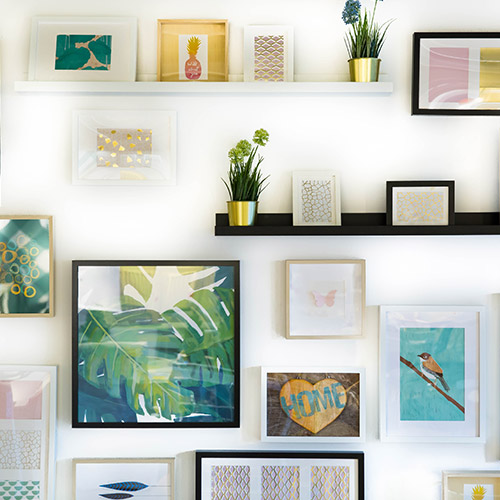 how-to-help-your-child-get-on-the-property-ladder-500x500 A neatly organised wall with many picture frames and a shelf with a plant pot.
