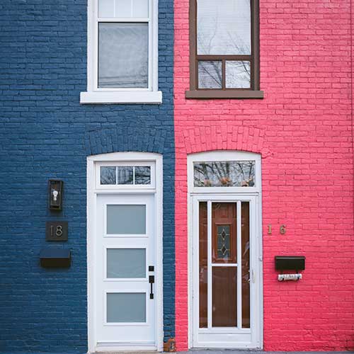 The front of two terraced houses, one with a blue front, the other pink