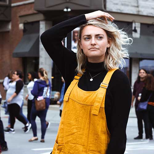 A young lady on a busy street, thinking about something