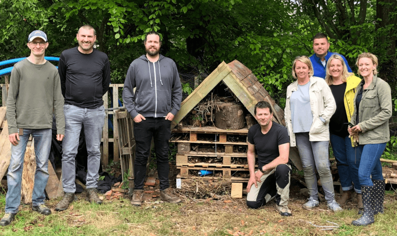 Volunteering_Stanmer_May2022_800x476px OneFamily staff posing for a picture next to a bug hotel at at Stanmer Wellbeing Gardens