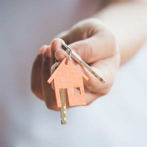 A hand holding a set of keys with a house-shaped keyring