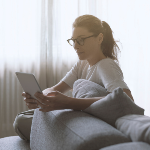Stock_woman_tablet_500x500 Woman sat on a sofa using a laptop