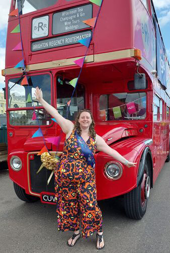 Emma in front of a vintage bus during Age UK's 65th birthday celebrations