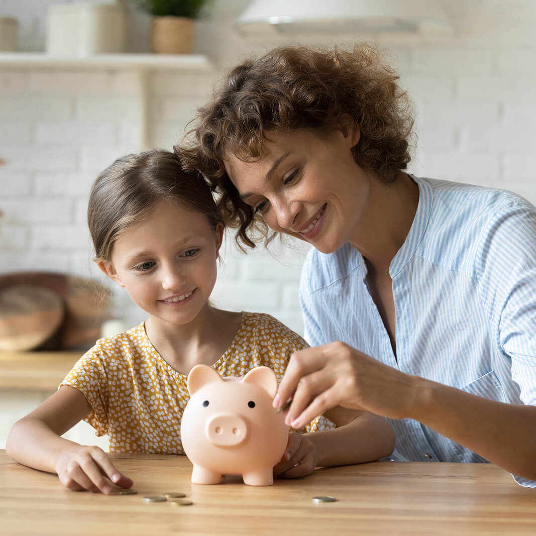 Setting good example. Young parent mother teach child little daughter girl to manage finances save money spend earnings with economy plan family budget. Friendly mum and kid thrift coins in piggybank