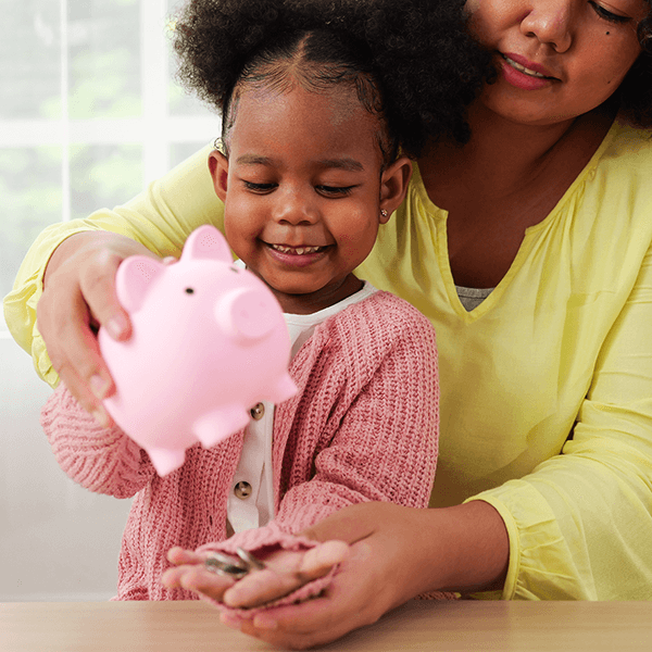 Mother helping young daughter empty piggy bank