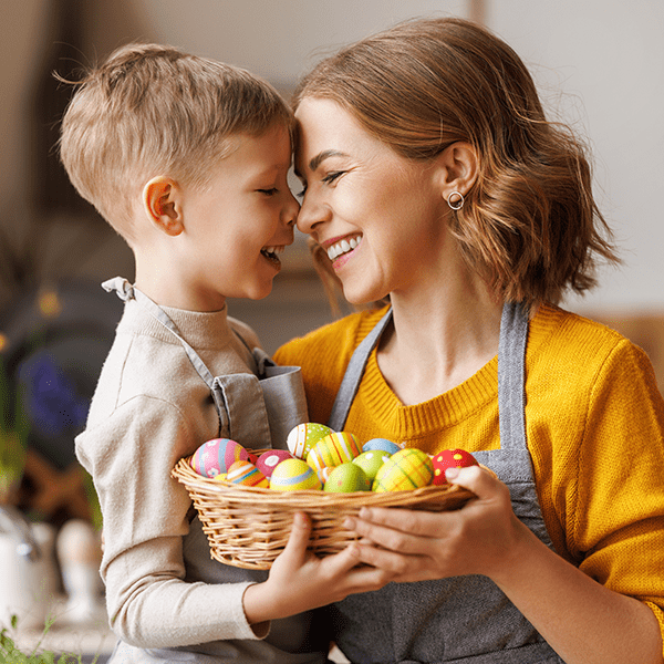 Mother and young son smiling holding basket of Easter eggs