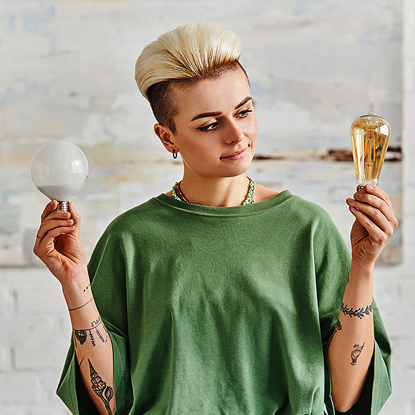 Young woman comparing two light bulbs in her hands