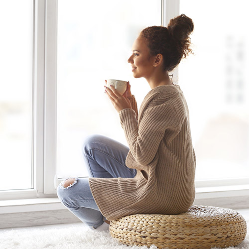 Woman sitting cross-legged on the floor drinking tea calmly