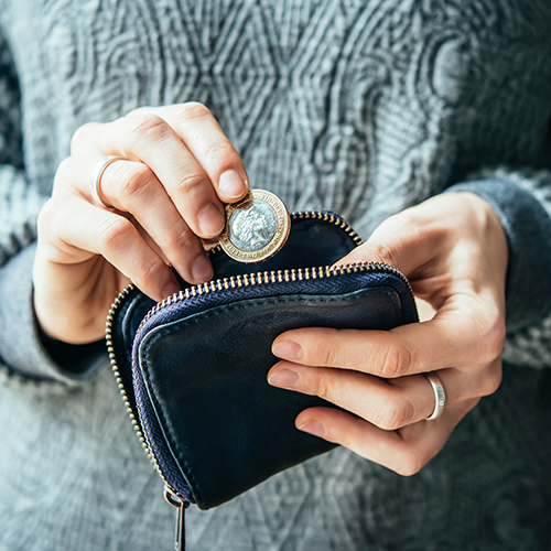 Hands holding british pound coin and small money pouch