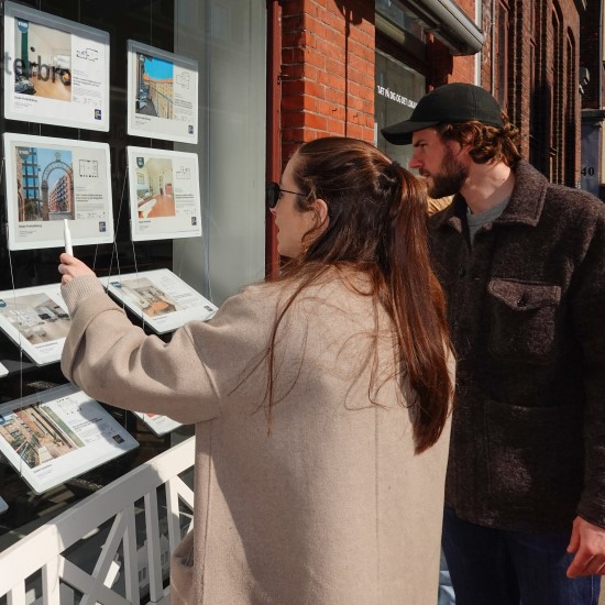 Two people looking at an estate agent window display