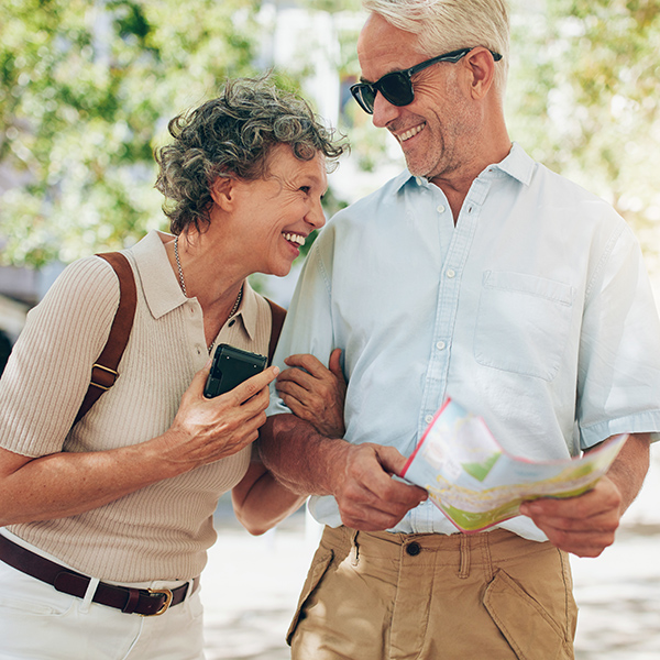 Retired couple walking around the town with a map. Smiling mature man and woman roaming around the city.