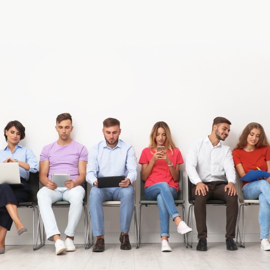 Stock_investing_funds_multi-investors_550x550 Group of people sat in a line using laptops and phones to invest in funds