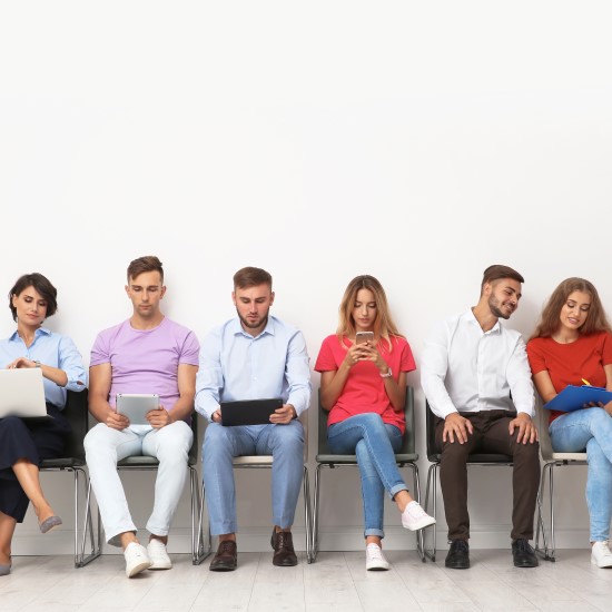 Group of people sat in a line using laptops and phones to invest in funds