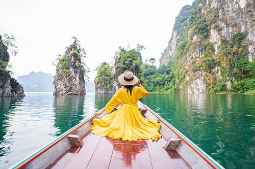 travel-experience-member-benefits-onefamily Woman in yellow dress on a boat in Vietnam