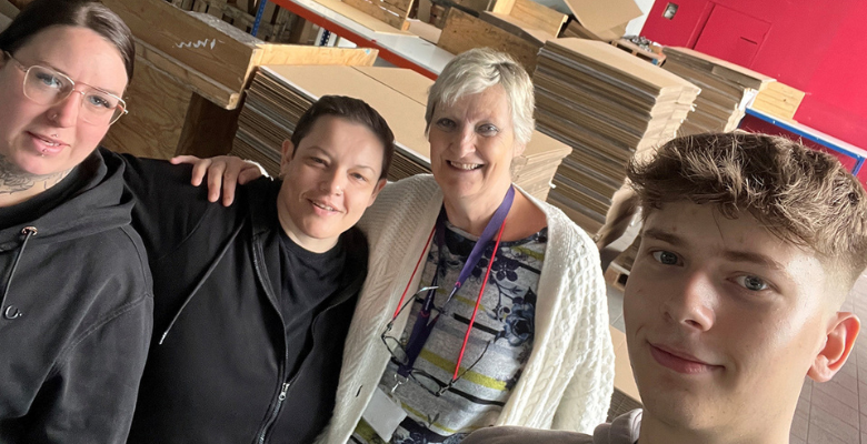 Four volunteers from OneFamily stood together at Phoenix Enterprises