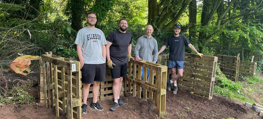 Group of four OneFamily team members leaning on a fence at Stanmer Community Gardens