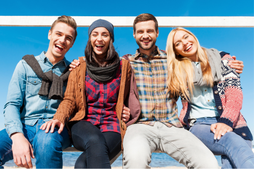 Four friends in their 20s laughing and smiling for the camera