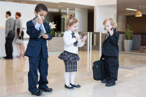 Three cute children dressed in office wear, holding briefcases and clipboards and talking into phones