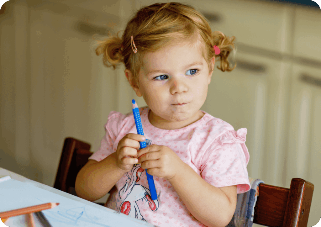Young child sitting at a table thinking and holding pencil.