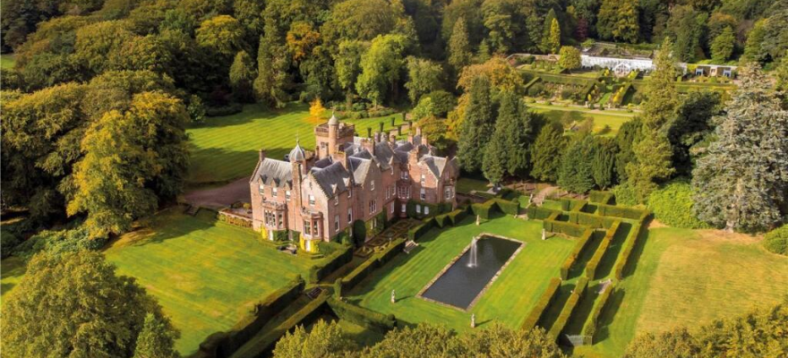 Huge estate in the Scottish highlands surrounded by trees, grass and a fountain