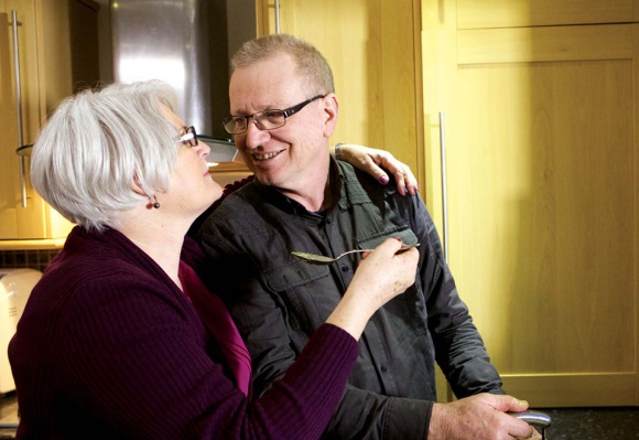 claims-experience An elderly couple hug at the kitchen sink