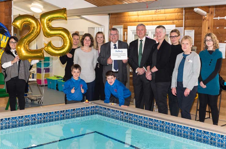 Foundation employees and staff members stand around a hydrotherapy pool