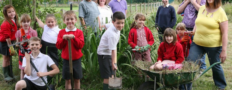 A group of children pose with gardening implements