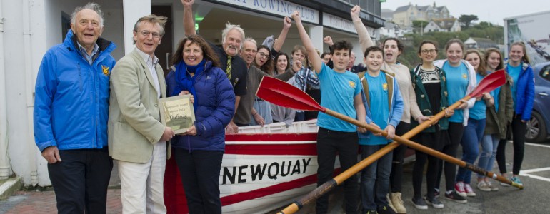 Rowers stand outside Newquay Rowing Club with their oars