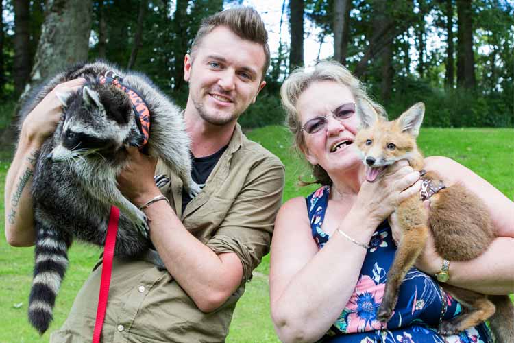party-animal-encounters A man and woman post with a raccoon and a fox