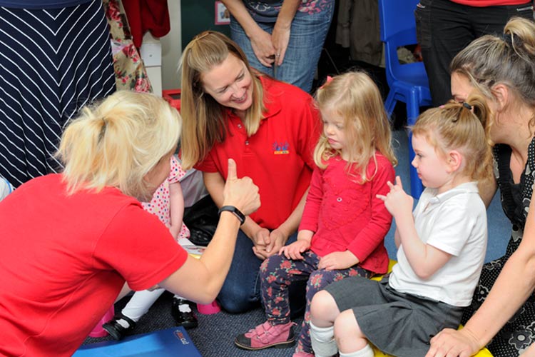 A women gives a thumbs up to playgroup children