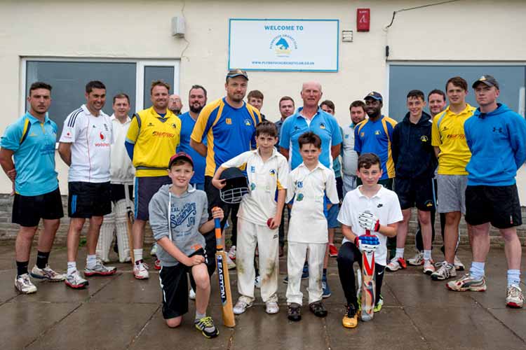 Cricket club members stand in front of their clubhouse