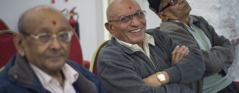 Three men sitting on chairs, smiling