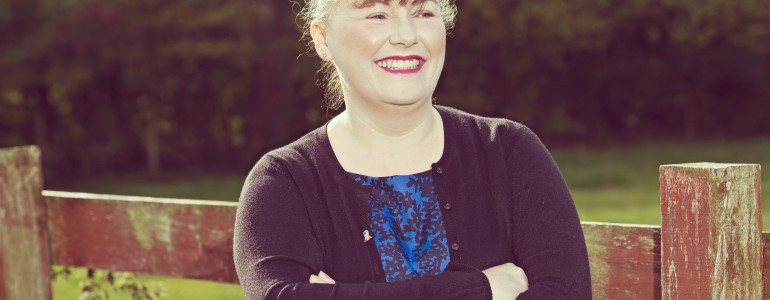 A smiling woman standing in front of a field
