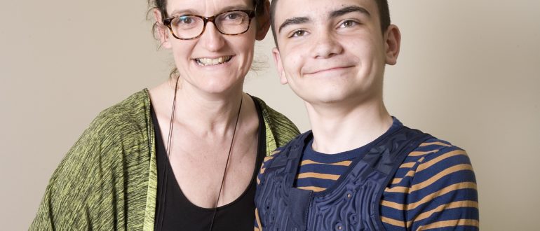rachel-hopkinson A woman in spectacles stands smiling with a young boy